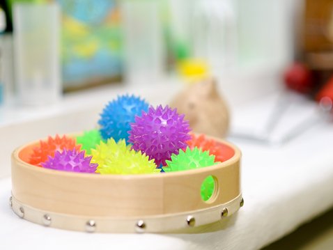 Mehrere bunte Igelbälle liegen in einer umgedrehten Tambourin auf einer Fensterbank