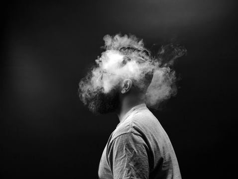 Mann mit rauchendem Kopf vor schwarzem Hintergrund