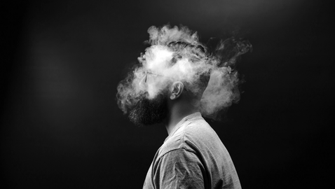 Mann mit rauchendem Kopf vor schwarzem Hintergrund