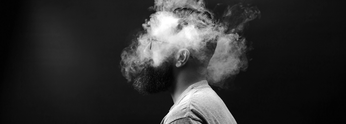 Mann mit rauchendem Kopf vor schwarzem Hintergrund